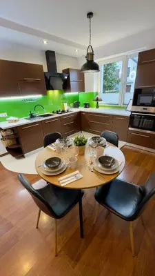 a kitchen with a table and chairs and a kitchen with green at Apartamenty Oracka Przystań Solna 2 in Bochnia