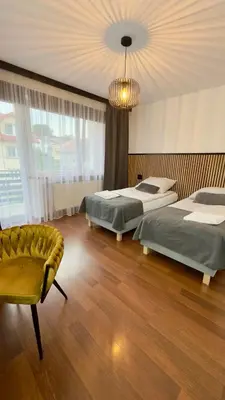 a bedroom with two beds and a couch and a chandelier at Apartamenty Oracka Przystań Solna 2 in Bochnia