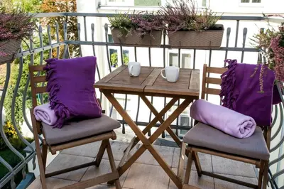 two chairs and a table on a balcony with purple pillows at Vanilla 4, 3bdr 1,5bth apartment in city centre in Kraków