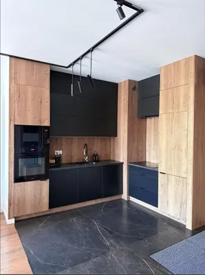 a kitchen with black counters and wooden cabinets at Novum Escape in Kraków