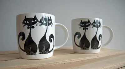 two coffee mugs with black and white cats on them at Sereno Apartments in Kraków
