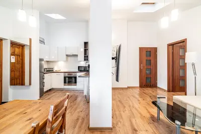 an open kitchen and living room with white walls and wooden floors at RentPlanet - Apartament przy Plantach in Kraków