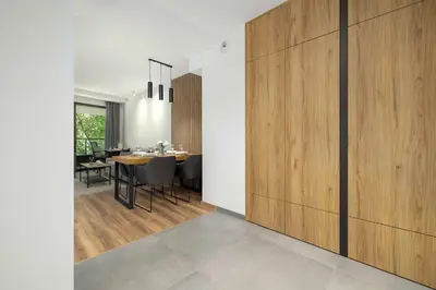 a dining room with a table and a wooden wall at Cosy Apartment in Cracow with Parking, Desk and Balcony by Noclegi Renters in Kraków