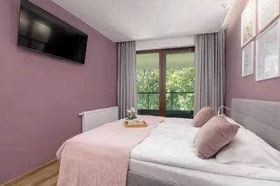 a bedroom with a bed with a tv on the wall at Cosy Apartment in Cracow with Parking, Desk and Balcony by Noclegi Renters in Kraków