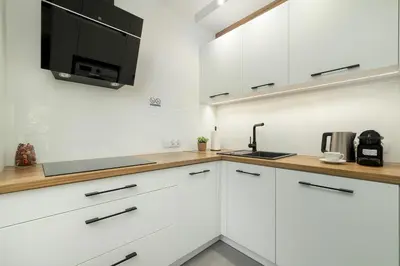 a white kitchen with white cabinets and a microwave at Cosy Apartment in Cracow with Parking, Desk and Balcony by Noclegi Renters in Kraków