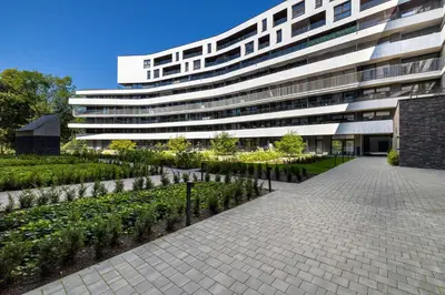a large white building with a garden in front of it at Cosy Apartment in Cracow with Parking, Desk and Balcony by Noclegi Renters in Kraków