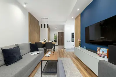 a living room with a couch and a large tv at Cosy Apartment in Cracow with Parking, Desk and Balcony by Noclegi Renters in Kraków