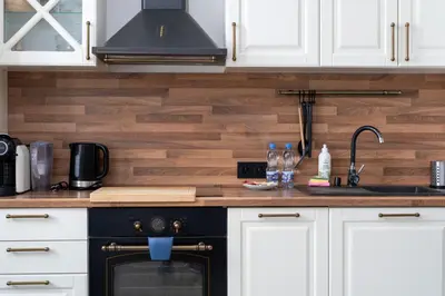 a kitchen with white cabinets and a black stove top oven at Starowiślna Harmony Apartment by BookingHost in Kraków