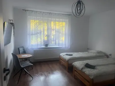 a bedroom with two beds and a chair and a window at u Wiktorii in Sąspów