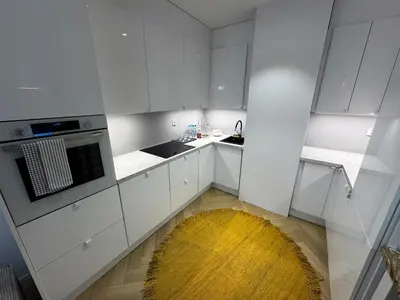 a kitchen with white cabinets and a yellow rug at Piltza House in Kraków