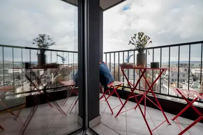 a person sitting at a table on a balcony at Central Luminis Comfort Kraków 2 in Kraków