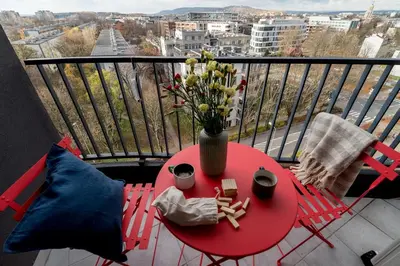 a red table with a vase of flowers on a balcony at Central Luminis Comfort Kraków 2 in Kraków