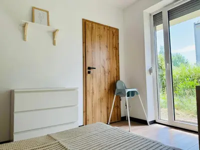 a bedroom with a bed and a door with a chair at Best Rest Kraków in Kraków