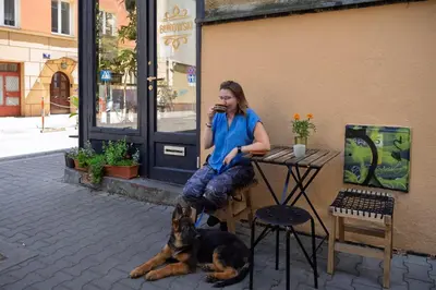a woman sitting at a table next to a dog at Apartament Green Old Town Krakow in Kraków
