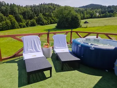 two chairs and a hot tub on a deck at Chatka Przytulasek in Męcina