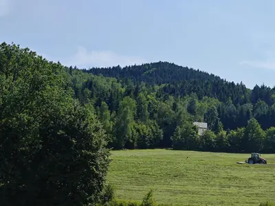 a tractor in a field in front of a mountain at Chatka Przytulasek in Męcina