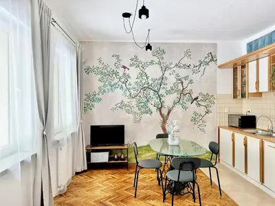 a kitchen with a table and a tree mural on the wall at GREEN APARTMENTS #Kazimierz, building C in Kraków