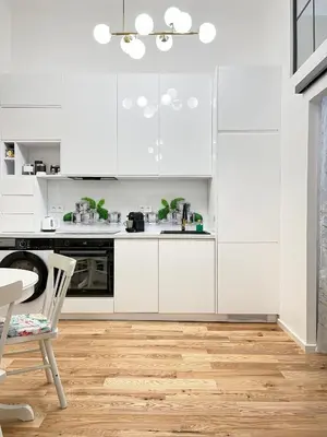 a white kitchen with white cabinets and a wooden floor at Premium & Quiet Apartment next to Main Square in Kraków