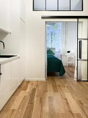 a kitchen with white cabinets and a wooden floor at Premium & Quiet Apartment next to Main Square in Kraków