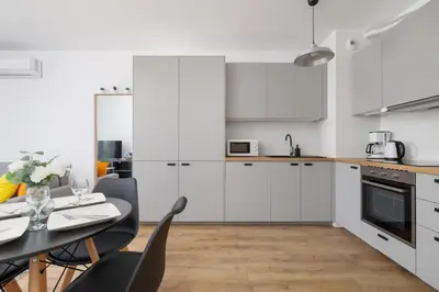 a kitchen with white cabinets and a table and chairs at Wybickiego Stylish Apartments with Parking and Air Conditioning in Cracow by Noclegi Renters in Kraków