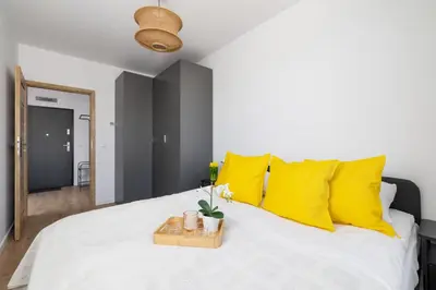 a bedroom with a white bed with yellow pillows at Wybickiego Stylish Apartments with Parking and Air Conditioning in Cracow by Noclegi Renters in Kraków