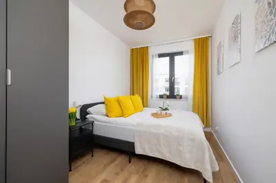 a bedroom with a bed with yellow pillows and a window at Wybickiego Stylish Apartments with Parking and Air Conditioning in Cracow by Noclegi Renters in Kraków