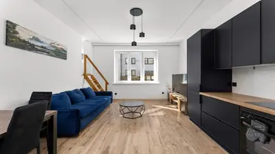 a living room with a blue couch and a kitchen at Pleszowska Urban Elegance Apartments by BookingHost in Kraków