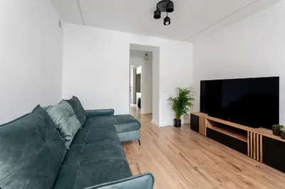 a living room with a green couch and a flat screen tv at Pleszowska Urban Elegance Apartments by BookingHost in Kraków