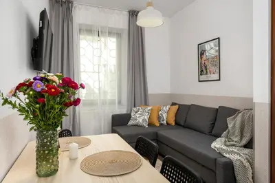 a living room with a couch and a table with flowers at Hala Targowa Apartments in Kraków