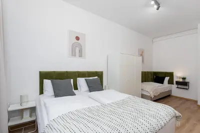 a bedroom with a large white bed with a green headboard at Hala Targowa Apartments in Kraków