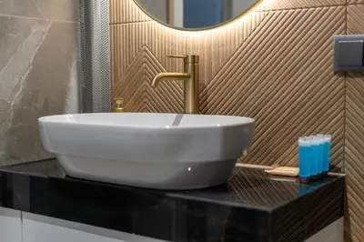 a white sink on a black counter in a bathroom at Osiedle Willowe Vintage Chic Apartment by BookingHost in Kraków