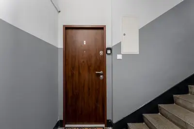 a wooden door in a hallway with stairs at Osiedle Willowe Vintage Chic Apartment by BookingHost in Kraków
