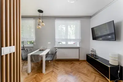 a dining room with a white table and a tv at Osiedle Willowe Vintage Chic Apartment by BookingHost in Kraków