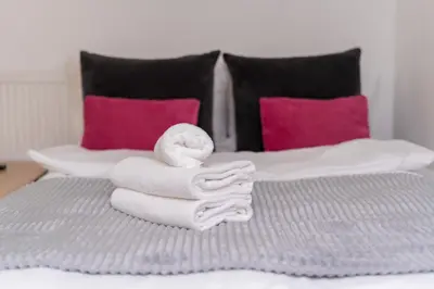 a pile of towels on a bed with pink pillows at Morsztynowska Studio with Mezzanine by BookingHost in Kraków