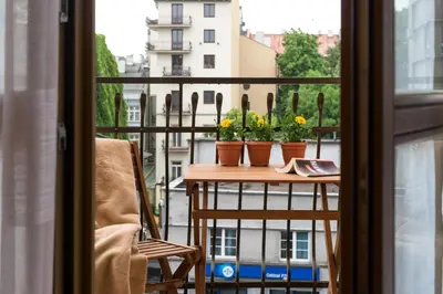 a balcony with a table with flowers on it at Vanilla Apartments - 3 spacious apartments 5min to Main Square in Kraków