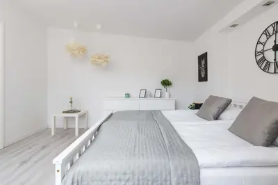 a white bedroom with a large bed and a clock at Spacious Apartment in Wieliczka with AC & Parking in Wieliczka