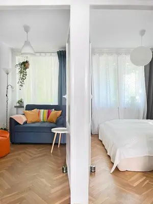 a white bedroom with a bed and a blue couch at Cozy Apartment 10 minutes to Wawel Castle in Kraków