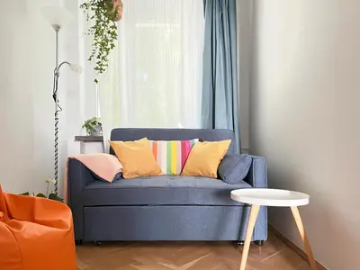 a blue couch with colorful pillows in a living room at Cozy Apartment 10 minutes to Wawel Castle in Kraków