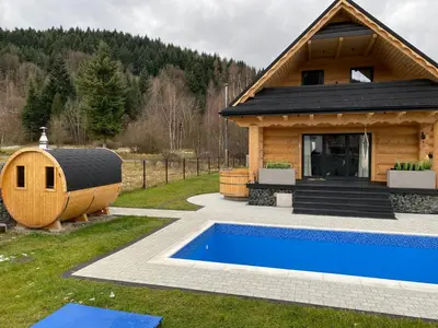 a cabin with a swimming pool next to a house at Chata pod Groniem in Skawica
