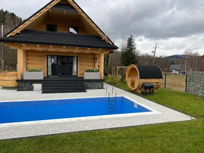 a log cabin with a swimming pool in front of a house at Chata pod Groniem in Skawica
