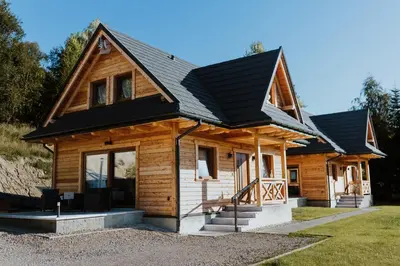 a log cabin with a black roof at Hajdukówka Domki in Stróża
