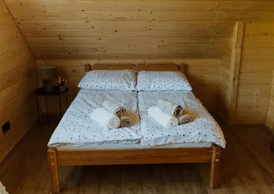 a bed in a wooden room with towels on it at Hajdukówka Domki in Stróża