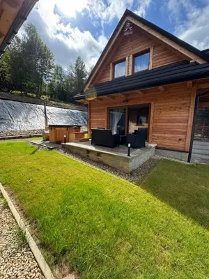 a wooden house with a lawn in front of it at Hajdukówka Domki in Stróża