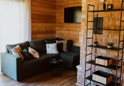 a living room with a couch and a brick wall at Hajdukówka Domki in Stróża