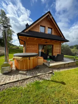 a log house with a hot tub in the yard at Hajdukówka Domki in Stróża