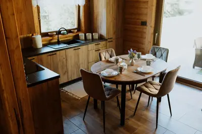 a kitchen with a table with chairs and a sink at Hajdukówka Domki in Stróża