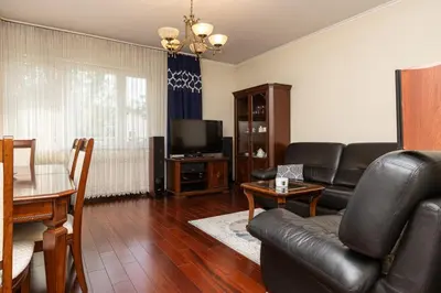 a living room with a black leather couch and a television at Apartament Kraków - Cracow Apartment 70m2 in Kraków