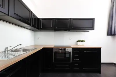 a kitchen with black cabinets and a sink at Krupnicza 10 by Homeprime in Kraków