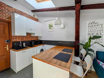 a kitchen with white cabinets and a wooden counter top at Dwernickiego 7 by Homeprime in Kraków