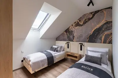 two beds in a attic bedroom with a window at Balice Apartamenty Premium - by Upstairs in Cholerzyn
